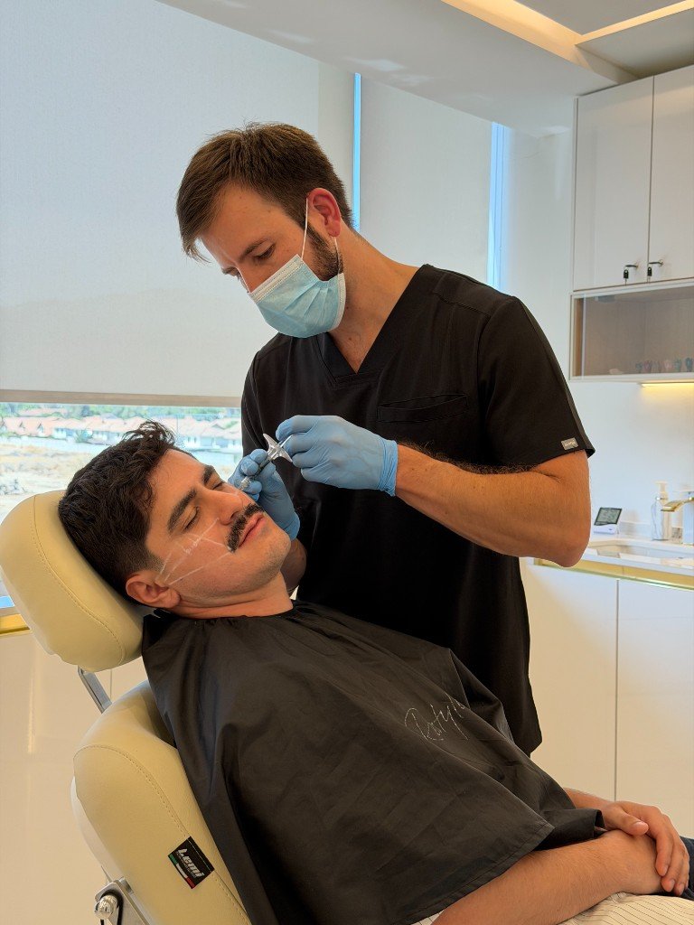 Procedimiento facial en paciente masculino: profesional aplica tratamiento con marcas guía en mejilla